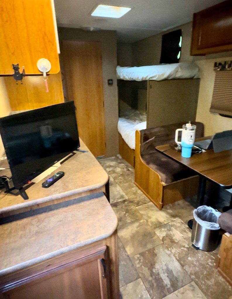 Main space inside 21’ Bunkhouse rental from RV Share at the Campsites at Disney's Fort Wilderness Resort with kitchen table, bunks and tv