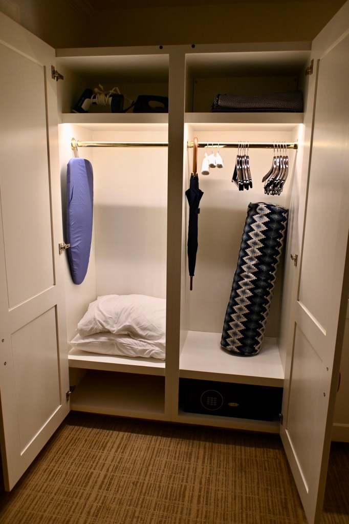view inside the closet with an ironing board, extra pillows and blankets inside the King Vista suite at the Tides Inn in Irvington, Virginia