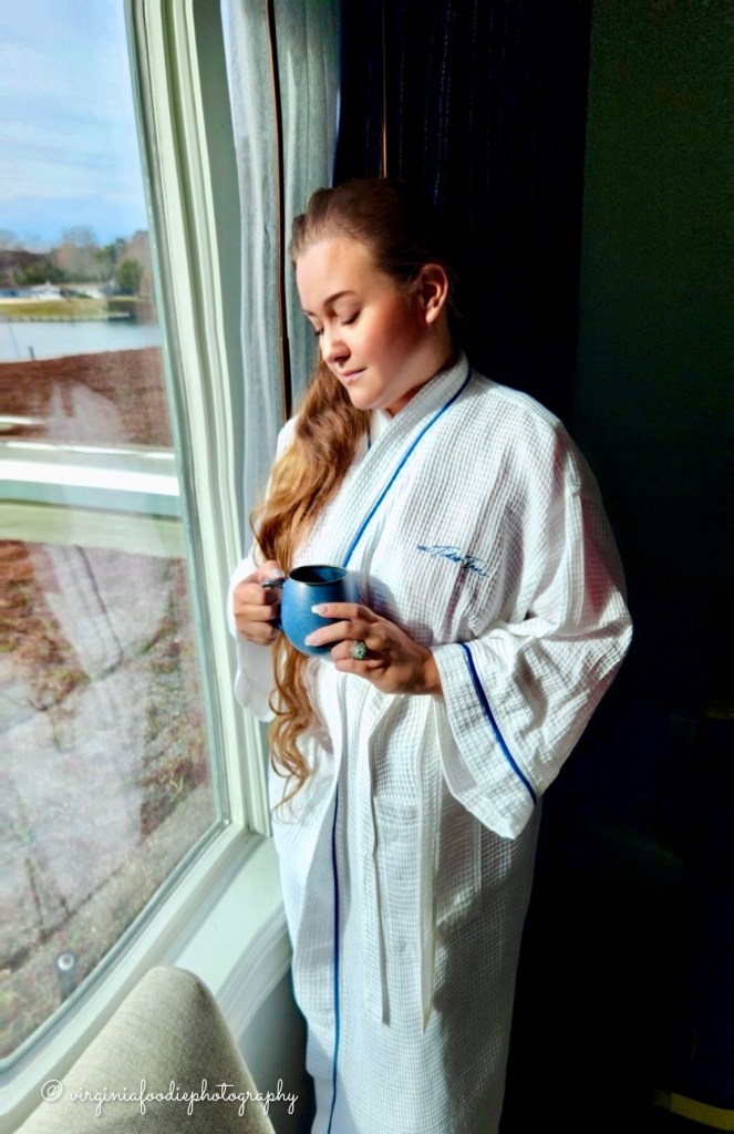 the Virginia hype girl holds a cup of coffee looking out over Carter’s Creek from inside of the King Vista suite at the Tides Inn in Irvington, Virginia
