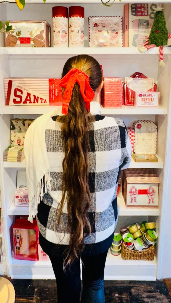 theVirginiahypegirl in a sweater with a Christmas bow in her hair, looking at Christmas notes and cards